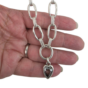 Close-up of a silver-plated Turkish necklace showing textured oval links and a faceted smoky brown heart pendant for size and detail.