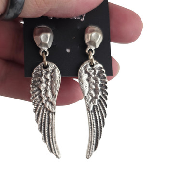 Wing silver-plated post dangle earrings in my hand. 