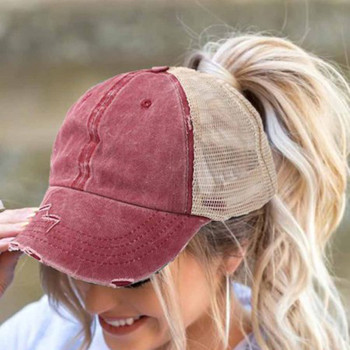 Woman wearing a faded burgundy distressed baseball cap with tan mesh back, curved bill and high ponytail opening.