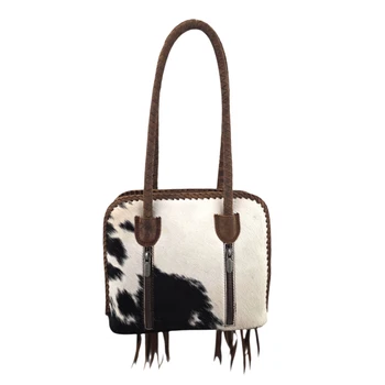 Loyal West Suave black and white hair-on cowhide leather shoulder bag featuring braided brown leather handles, decorative edging, and two vertical zippered pockets.