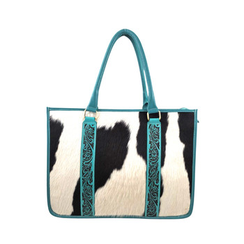 Myra Antonia Trail Leather Tote Bag featuring genuine black-and-white hair-on cowhide, vibrant turquoise leather trim, intricate Western floral scrollwork, double carrying handles, and antique-style hardware.