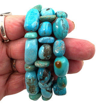Three turquoise nugget elastic stretch bracelets displayed in hand, featuring polished sky blue, aqua, and teal stones with unique earthy matrix patterns.