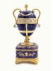 Faberge Serpent Clock Egg. A royal purple replica enamel egg of the original blue enamel egg, which was presented by Nicholas II to his mother, Maria Feodorovna, on Easter day, 1895. It features a "cercles tournants" (revolving dial) urn clock in the Louis XVI style with a snake to indicate the time. Currently, the original is owned by Prince Albert II, Prince Rainier III's son, and held in Monaco. 5¾" in height, 2" square base, slightly over 1 pound. Top half removes completely.