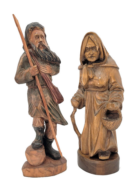 Peasant Couple, Poland. Detailed larger linden wood carvings of a man carrying a staff and a shoulder bag and a woman carrying a basket and a walking stick. His right foot rests on a rock. Both are dressed for mountain climbing. Written on the bottoms of each is "Poland 1992". This may indicate when they were purchased or when they were made. The style of the carvings appears to be older, perhaps somewhere post-WWII. Unusual, to say the least.