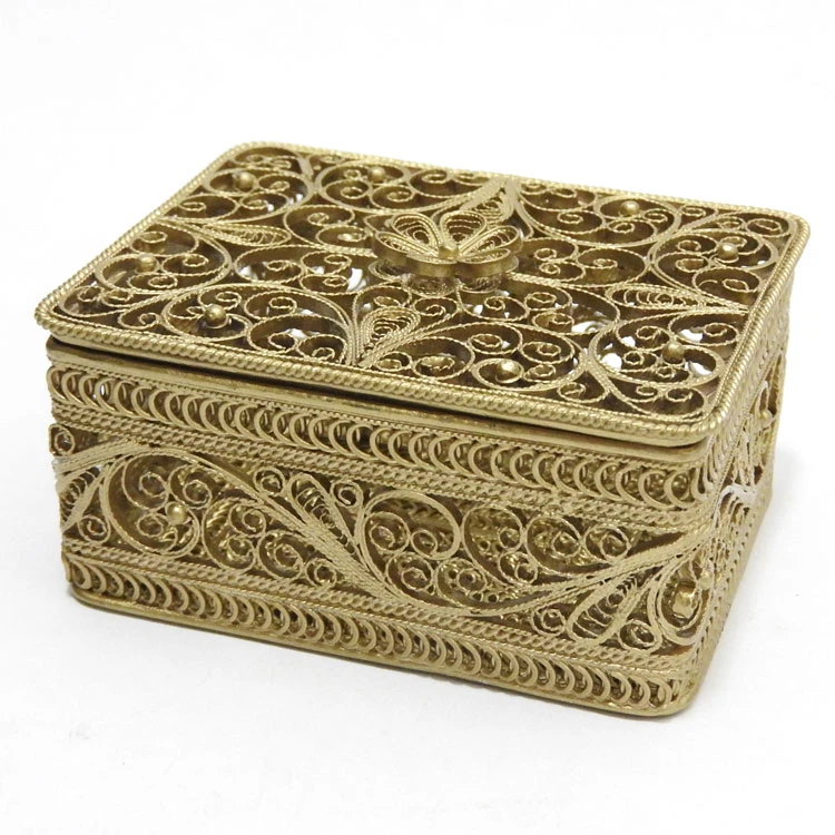 Golden Filigree Box. This elegant box was made entirely by hand, and not by a machine. It is a fine example of design and craftsmanship that was perfected in the days of Empress Catherine the Great (1762-1796). The pattern is reminiscent of bobbin-lace, and the artisans who created this style named it "Dew Drop" (in Russian, "Росинка"). It is hand decorated with tiny round pellets called "seed pearls" ("семенные жемчужины") and capped with a hand made rosette on the lid. Made the village of Kazakovo, near Nihzny Novgorod, a center of fine filigree work for decades. The box comes in it's original, Soviet-style box. 3"x2"x1¼".