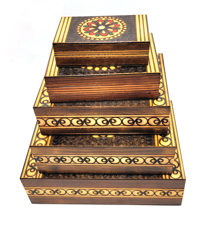 Set of 5 nested wooden Polish boxes. Crafted in Zakopane (Podhale region), a town which lies at the foothills of the Tatra Mountains. Each box is identically carved and stained with decorations incised using the techniques of the craft of traditional pyrography (woodburning). Boxes are lined with bright red felt (a nice touch), and nest perfectly within one another. The center of each box is a spiral flower with red and green enhancements and the surrounding wood is intricately textured. Three largest boxes have elaborate edge borders. An unusual set in brand new condition.