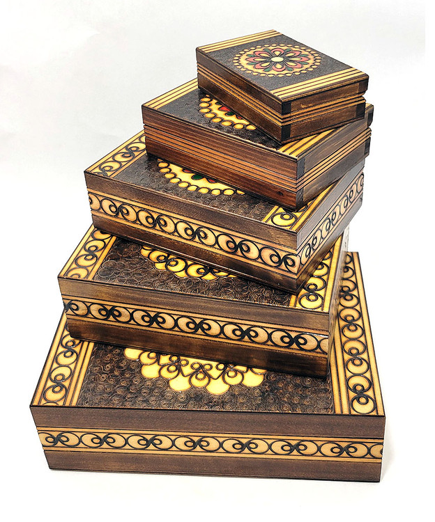 Set of 5 nested wooden Polish boxes. Crafted in Zakopane (Podhale region), a town which lies at the foothills of the Tatra Mountains. Each box is identically carved and stained with decorations incised using the techniques of the craft of traditional pyrography (woodburning). Boxes are lined with bright red felt (a nice touch), and nest perfectly within one another. The center of each box is a spiral flower with red and green enhancements and the surrounding wood is intricately textured. Three largest boxes have elaborate edge borders. An unusual set in brand new condition.