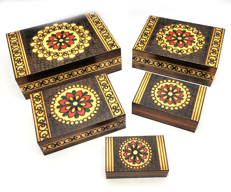 Set of 5 nested wooden Polish boxes. Crafted in Zakopane (Podhale region), a town which lies at the foothills of the Tatra Mountains. Each box is identically carved and stained with decorations incised using the techniques of the craft of traditional pyrography (woodburning). Boxes are lined with bright red felt (a nice touch), and nest perfectly within one another. The center of each box is a spiral flower with red and green enhancements and the surrounding wood is intricately textured. Three largest boxes have elaborate edge borders. An unusual set in brand new condition.