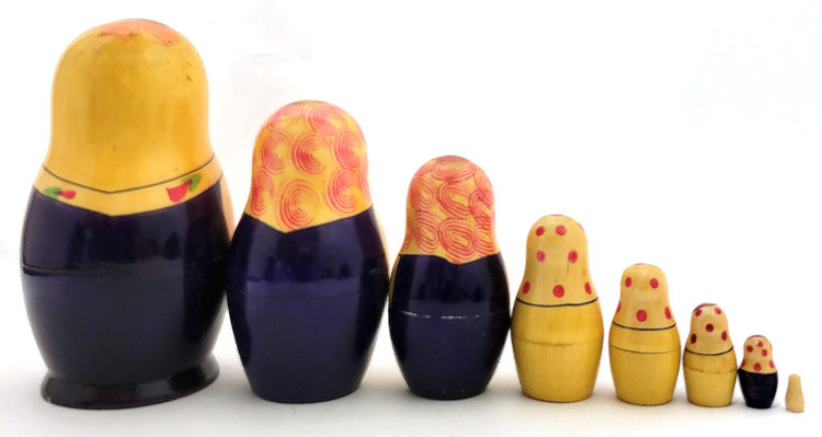 Kirov Purple Matryoshka, 8nest [1979]. Scarce color arrangement of an 8pc Kirov doll, circa 1977. This matryoshka set was made nearly 50 years ago, some 20 years after the formation of the production center itself. Any nesting dolls from the last quarter of the 20th century are somewhat scarce in about fine, unplayed with condition. Of note here is the continuation of the color purple dresses of the first three pieces, and one more near the end. The lines are sharp, as are the features, on the first four pieces, and the expressions are somber. The flowers, dots and swirls are numerous. The pieces all fit well. There is some age-related wear at the opening, but this can be color touched, if desired (we haven't). This is a highly collectible, 49 year-old set in about fine condition. 5⅝" down to tiny. The label reads (in part): Производственное объединение "Вятка" по выпуску игрушек г. Киров (Production association "Vyatka" for the production of toys, city of Kirov), plus a state mandated price, an article number and the export date (Oct 1983).  It's not easy to find information on how the Russian toy, specifically the Matryoshka doll, came to be the number one tourist and export item of the USSR era. The Russian, aka Soviet, toy production began courting the tourist trade in earnest sometime in the 1960s, when it encouraged small collectives and factories to produce souvenirs to be sold to non-Russians. It started slowly, but eventually built up speed as the Moscow 1980s Olympics was slated to welcome foreign, specifically from Europe and the West (aka USA), tourists. Interest in Russian handicrafts was also stoked by importers of said goods in the US and elsewhere.
