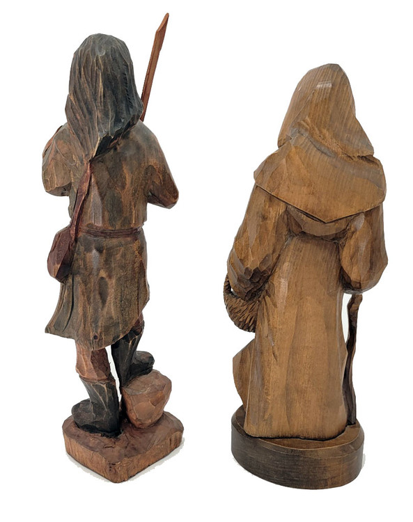 Peasant Couple, Poland. Detailed larger linden wood carvings of a man carrying a staff and a shoulder bag and a woman carrying a basket and a walking stick. His right foot rests on a rock. Both are dressed for mountain climbing. Written on the bottoms of each is "Poland 1992". This may indicate when they were purchased or when they were made. The style of the carvings appears to be older, perhaps somewhere post-WWII. Unusual, to say the least.