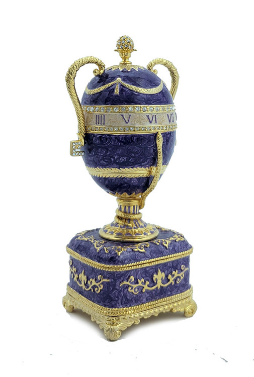 Faberge Serpent Clock Egg. A royal purple replica enamel egg of the original blue enamel egg, which was presented by Nicholas II to his mother, Maria Feodorovna, on Easter day, 1895. It features a "cercles tournants" (revolving dial) urn clock in the Louis XVI style with a snake to indicate the time. Currently, the original is owned by Prince Albert II, Prince Rainier III's son, and held in Monaco. 5¾" in height, 2" square base, slightly over 1 pound. Top half removes completely.