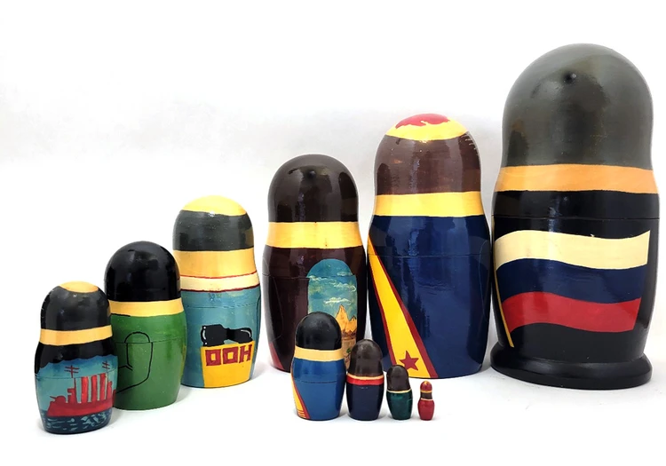 Yeltsin with Leaders (Ельцин с Вождями). The whole line of succession, from Yeltsin down to the beginning of the monarchy, is depicted in this 10 piece set. Larger dolls with more than 5 pieces are less common due to the cost of production.  A solemn Boris Yeltsin, the first post-Communist leader, heads off the caravan. A banner proclaims "Россия" (Russia) in red letter and the white, blue and red flag is painted on the back. Gorbachev in his characteristic blue suit has a yellow sash with the word Перестройка (Perestroika). His birthmark has the letters CCCP added. More leaders follow: 10 in all!