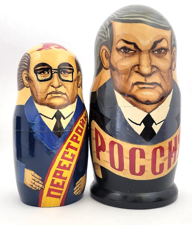 Yeltsin with Leaders (Ельцин с Вождями). The whole line of succession, from Yeltsin down to the beginning of the monarchy, is depicted in this 10 piece set. Larger dolls with more than 5 pieces are less common due to the cost of production.  A solemn Boris Yeltsin, the first post-Communist leader, heads off the caravan. A banner proclaims "Россия" (Russia) in red letter and the white, blue and red flag is painted on the back. Gorbachev in his characteristic blue suit has a yellow sash with the word Перестройка (Perestroika). His birthmark has the letters CCCP added. More leaders follow: 10 in all!