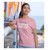 Young woman modeling 'In God I Trust' Christian T-Shirt in Light Pink, featuring Isaiah 26:3 scripture, unisex athletic fit.