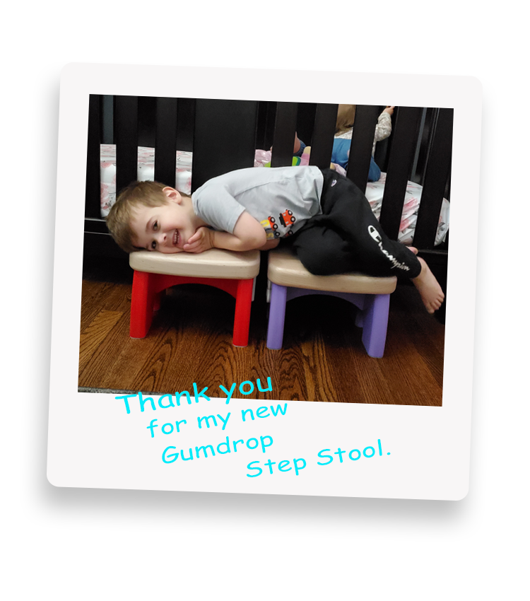 Little boy laying on top of two Gumdrop Step Stools.
