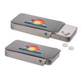 A silver slider tin containing sugar-free breath mints, with white mints visible beside it. The tin features a decorative logo.