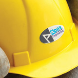 An oval resin-coated label featuring the text "Apex Engineering" is prominently displayed on a yellow hard hat.