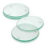 A set of four round glass coasters in a light green hue, featuring raised dots for grip.
