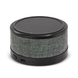 A round wireless speaker and charger with a textured grey fabric exterior and a sleek black top.