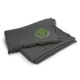 A green throw blanket with a fringed edge and a logo in the corner.
