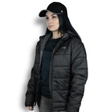 A woman wearing a black puffer jacket with a hood, paired with a black cap. The jacket features logo branding.