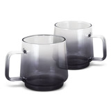 A set of two glass coffee mugs in a gradient of grey, featuring a sturdy handle and a smooth finish.