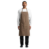 A brown canvas apron worn by a model, featuring a front pocket and adjustable neck straps.