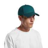 A teal cap worn by a person in a white t-shirt, featuring a logo on the front.