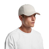 A plain cream-coloured Nylon cap worn by a model, featuring a curved brim and a logo.
