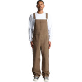 Canvas overalls in brown, featuring adjustable straps and a relaxed fit. Model is wearing them with a white long-sleeve shirt.