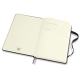 An open Moleskine 2026 planner with blank white pages and a black cover, featuring a ribbon bookmark and a branding logo.