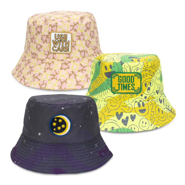 A collection of three bucket hats in pastel pink, bright yellow with patterns, and dark navy with celestial design, each featuring an embroidery patch.
