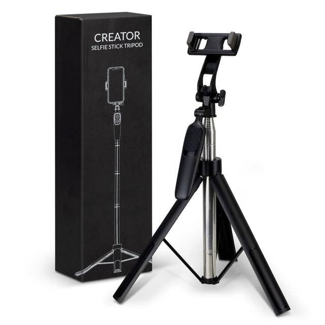 A black selfie stick tripod with a phone holder, next to its packaging, also in black.