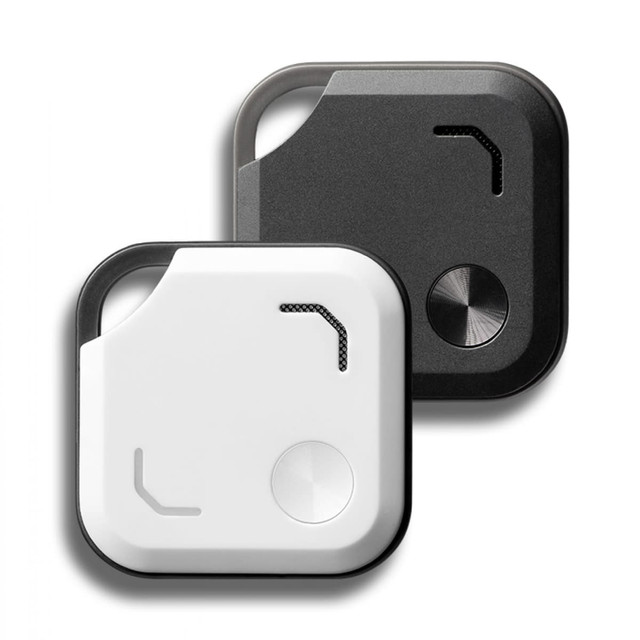 A pair of Bluetooth trackers in black and white, featuring a sleek design and circular button. Each has a logo.