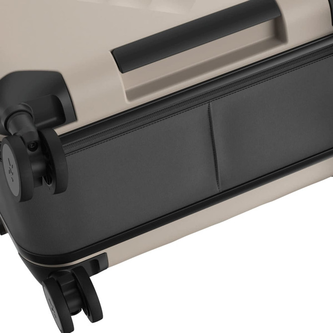 A wheeled suitcase in beige and black, featuring zippered compartments and dual wheels for smooth movement.