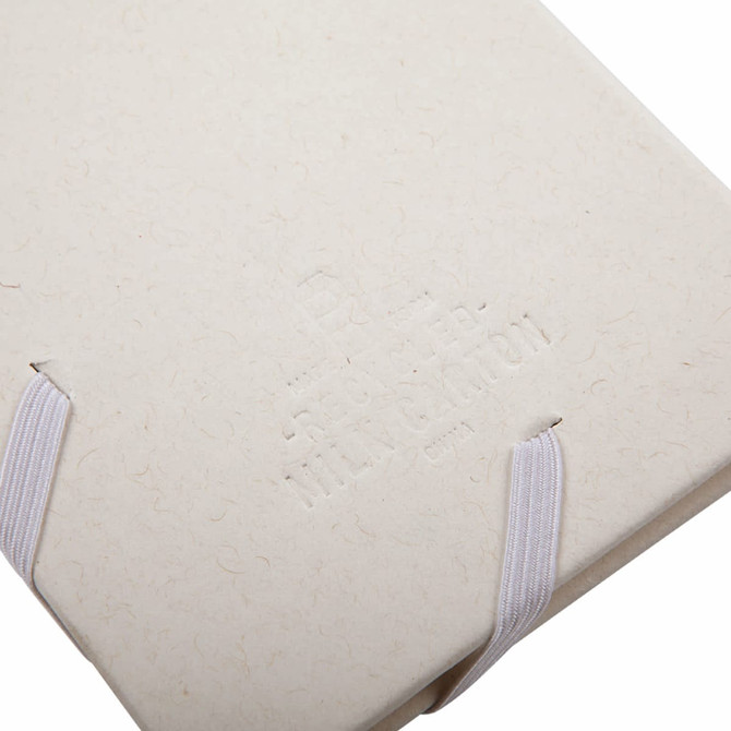 A cream-coloured planner with an elastic band closure and embossed branding on the cover.