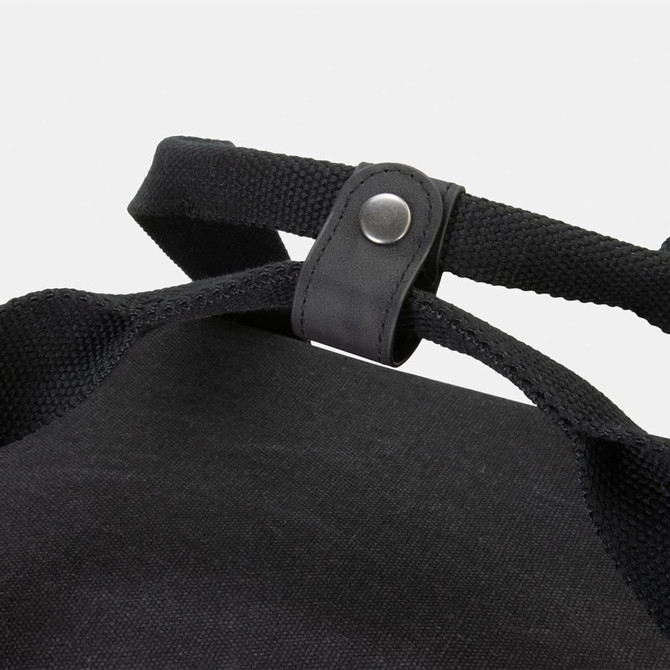 A black canvas cooler bag featuring sturdy straps and a snap button closure. It has a simple design with no visible branding.