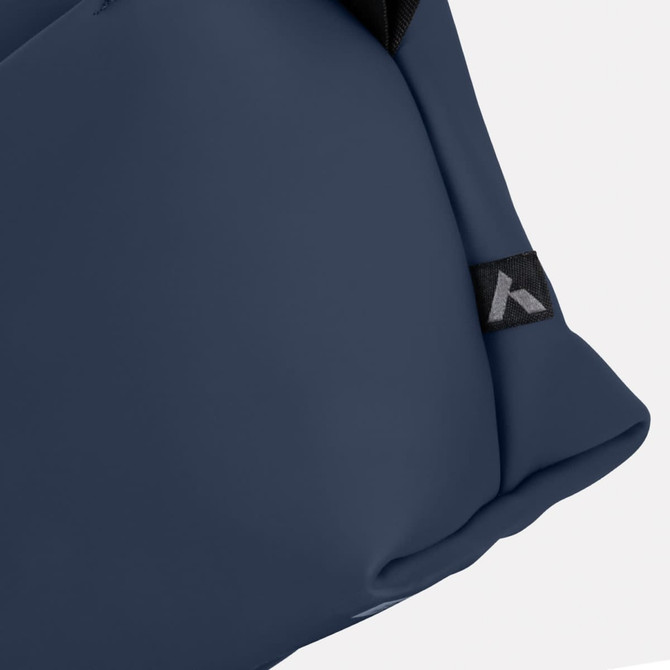 A navy soft-touch toiletry bag with a fabric tag featuring a logo.