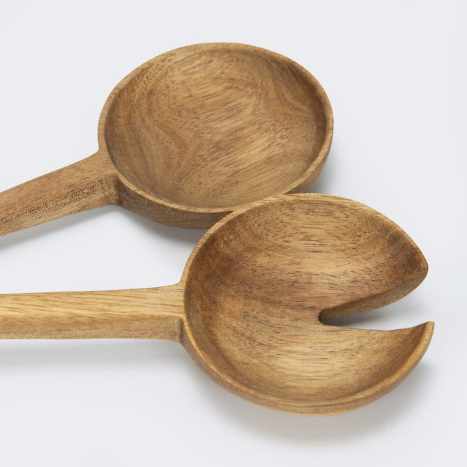 Two wooden salad servers in natural brown hues, featuring a spoon and a fork design, resting on a light background.