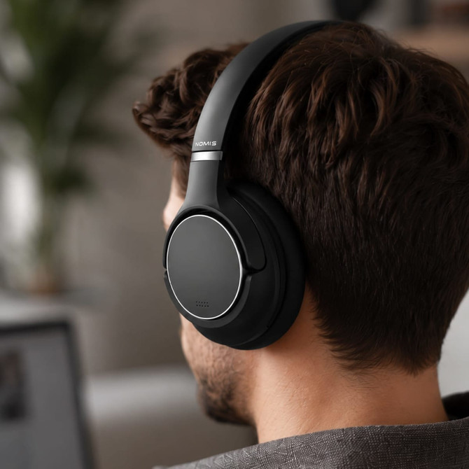 Black wireless headphones with a sleek design being worn by a person, featuring a subtle logo.