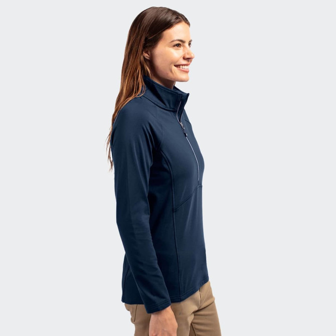 A women's half-zip top in navy blue, featuring a high collar and a fitted design. The model smiles while wearing it.
