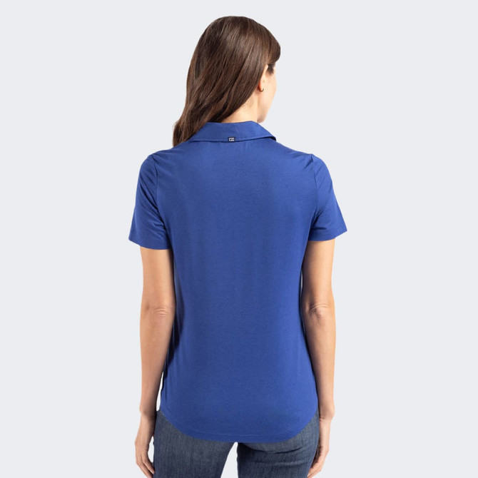 A back view of a blue women's polo shirt with a collared neckline. The shirt has a small logo near the collar.