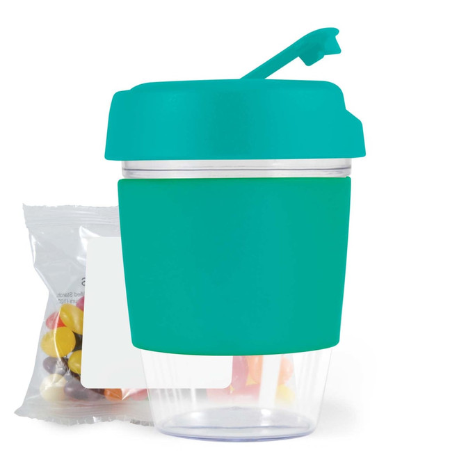 A reusable coffee cup with a teal silicone sleeve and lid, accompanied by a bag of jelly beans.