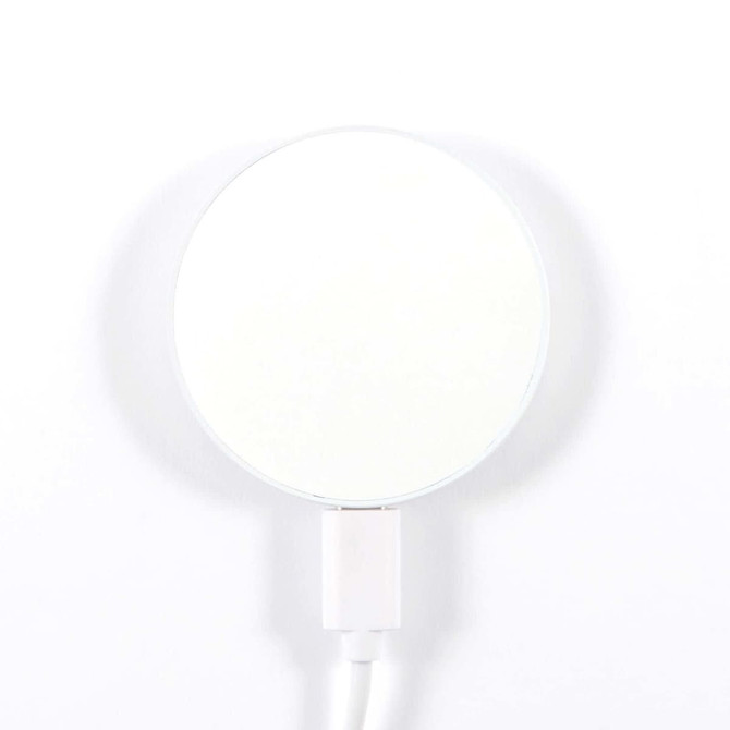A circular, magnetic wireless charger with a white surface and a white cable attached.