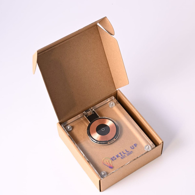A crystal wireless charger in a tan cardboard box, featuring a circular charging pad and a logo.