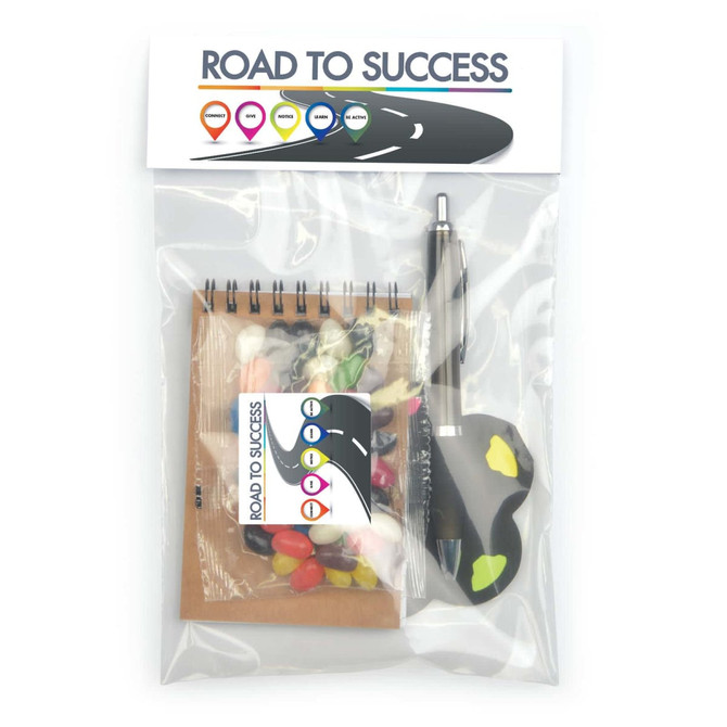 A promotional office pack featuring a notepad, a pen, and assorted colored candies, all packaged in a clear bag.