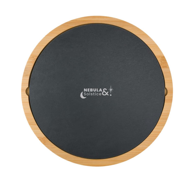 A round bamboo cheese board with a black slate top and a logo printed on it.