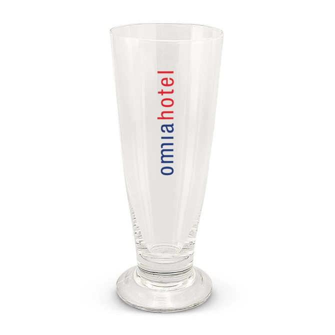 A clear beer glass with a tall, slender design and a base, featuring a logo in red and blue.