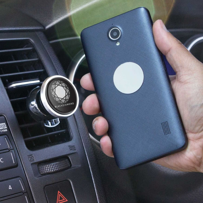 A dark blue smartphone held next to a silver magnetic phone holder attached to a car dashboard.