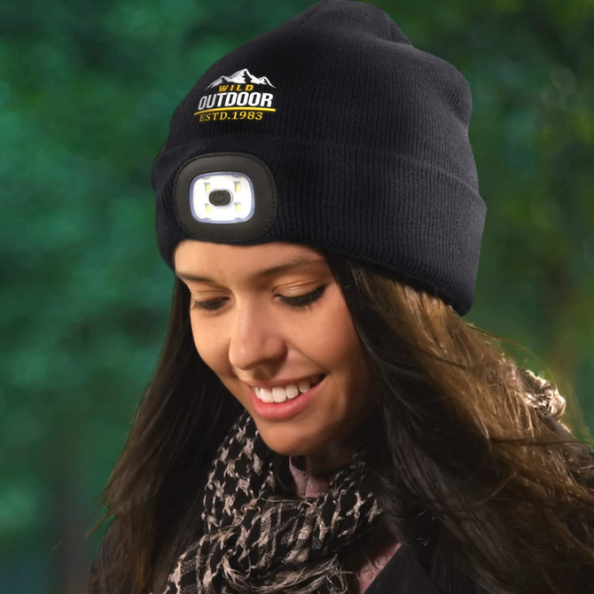 A black knitted beanie featuring an integrated headlamp at the front and a logo that reads "Outdoor ESTD.1983."